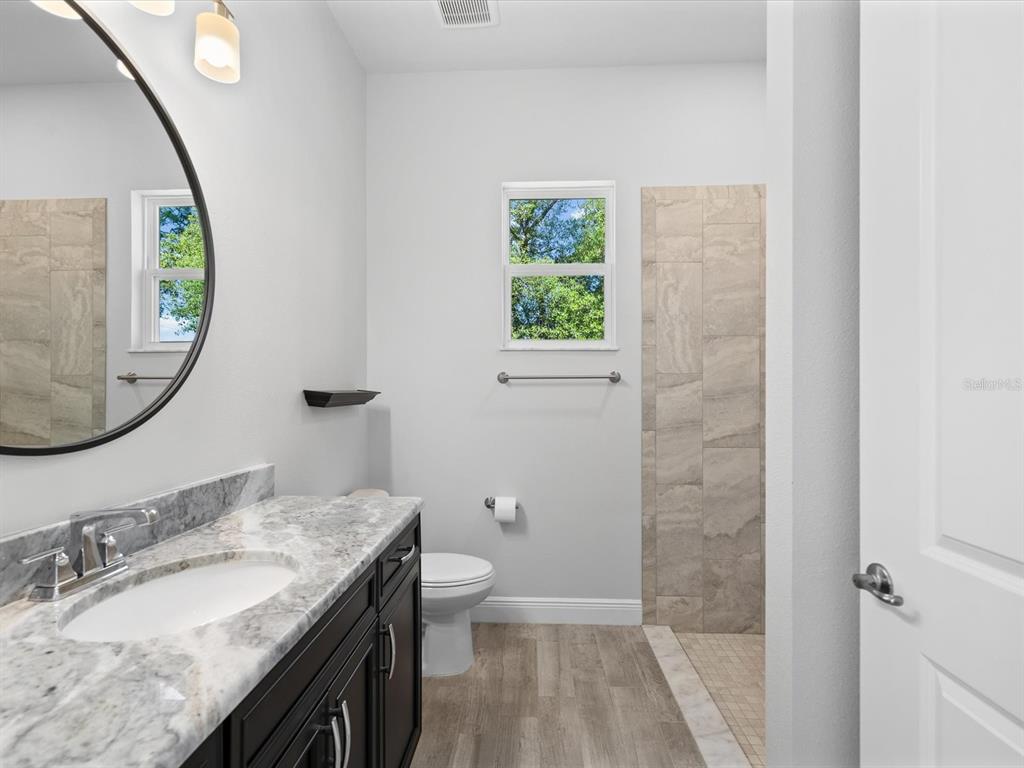11981 Robina Road Weeki Wachee, FL 34614 - Photo 44 of 93 a bathroom with a granite countertop sink a toilet and a mirror