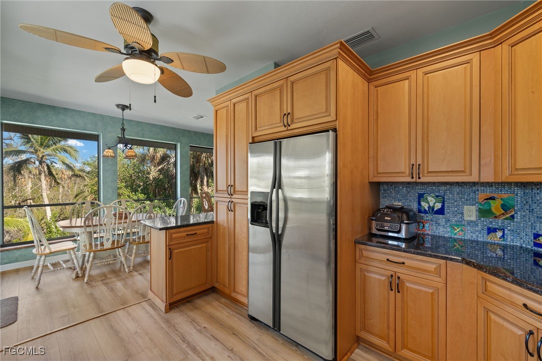 4631 Bowen Bayou Road Sanibel, FL 33957 - Photo 11 of 39 a kitchen with stainless steel appliances granite countertop a refrigerator a sink a dining table and chairs with wooden floor