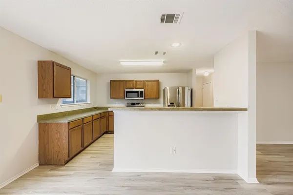 a kitchen with stainless steel appliances granite countertop a refrigerator a sink dishwasher and a oven with wooden floor