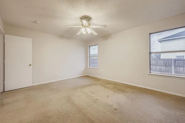 an empty room with windows and fan
