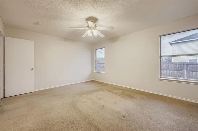 an empty room with a window and a fan