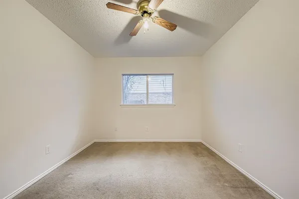 an empty room with a window and a fan