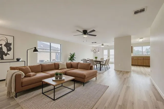 an empty room with wooden floor fan and windows