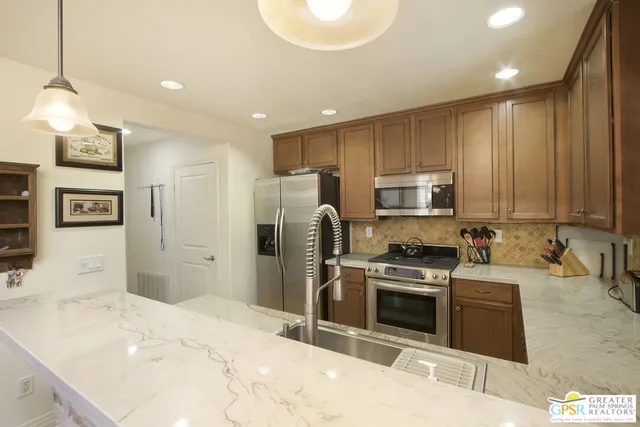 a kitchen with stainless steel appliances kitchen island granite countertop a stove a sink and a refrigerator
