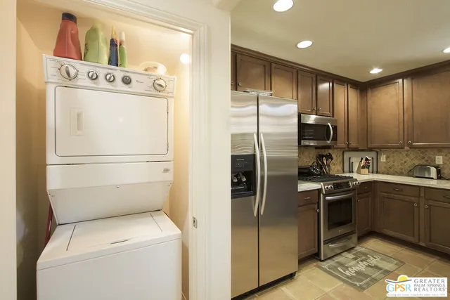 a kitchen with stainless steel appliances granite countertop a refrigerator a stove and a sink with wooden floor