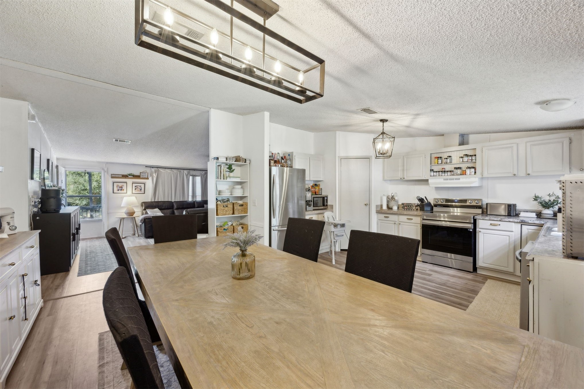 15461 Dewanna Road Jacksonville, FL 32218 - Photo 7 of 27 a kitchen with stainless steel appliances kitchen island granite countertop a refrigerator a stove top oven and a dining table with wooden floor
