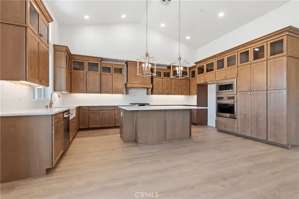 a large kitchen with a large counter top a sink stainless steel appliances and cabinets