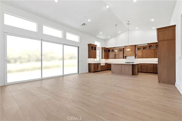 a large hall with stainless steel appliances kitchen island granite countertop a large window and a kitchen view