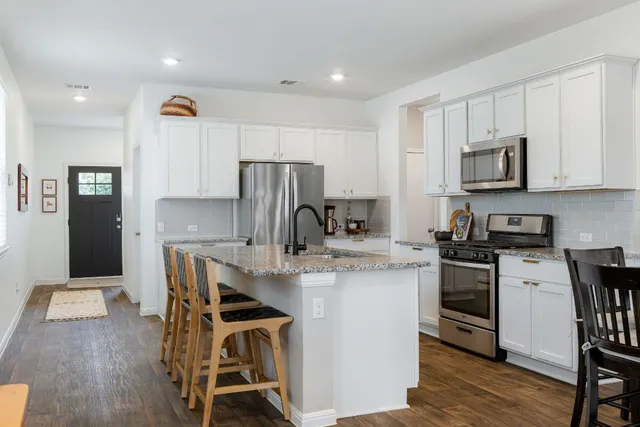 a kitchen with stainless steel appliances a microwave a stove a sink a refrigerator and cabinets