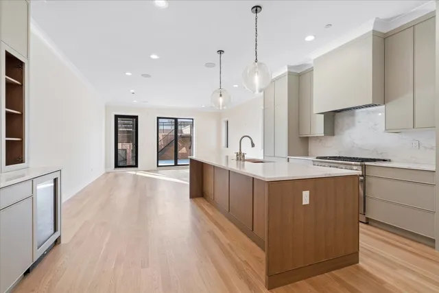a large kitchen with a large counter top a sink stainless steel appliances and cabinets