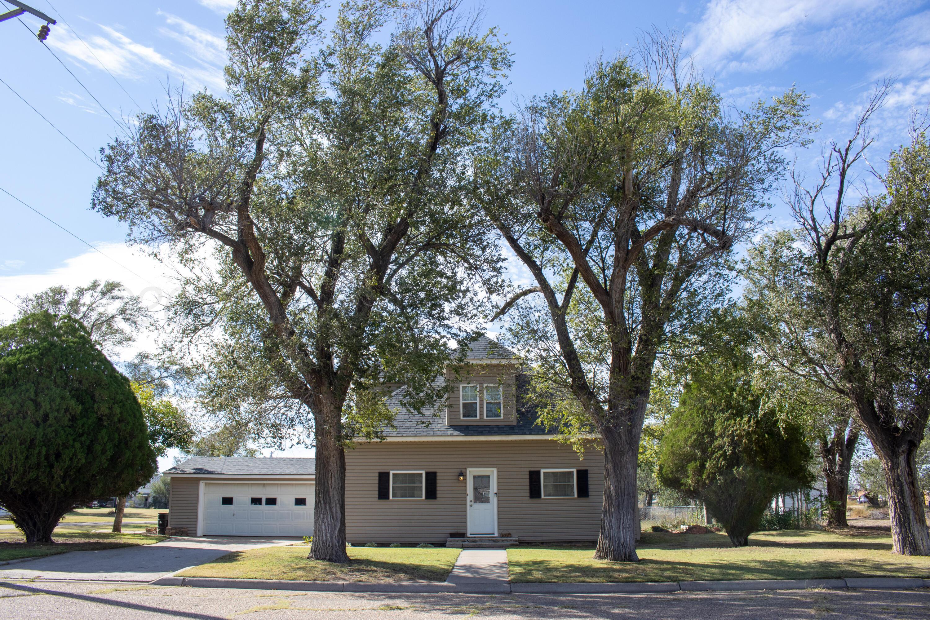 a front view of a house with a garden and tree