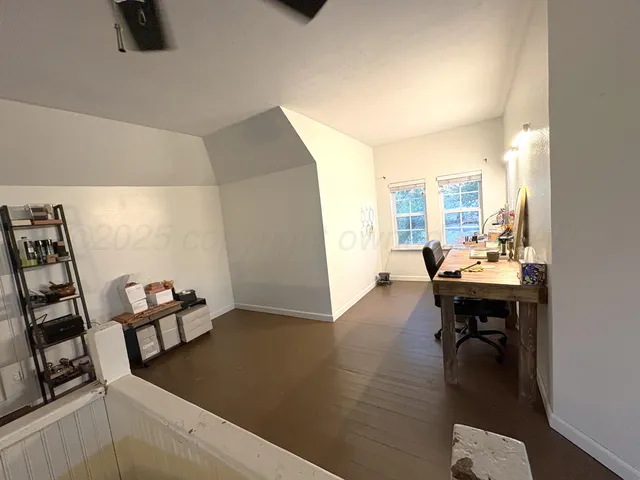 a view of a workspace with furniture and a ceiling fan
