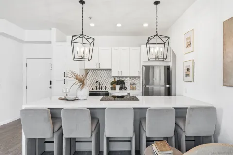 a kitchen with stainless steel appliances kitchen island granite countertop a dining table chairs and a refrigerator