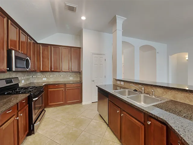a kitchen with stainless steel appliances granite countertop wooden cabinets a stove a sink and dishwasher