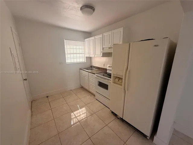 a kitchen with white cabinets and refrigerator