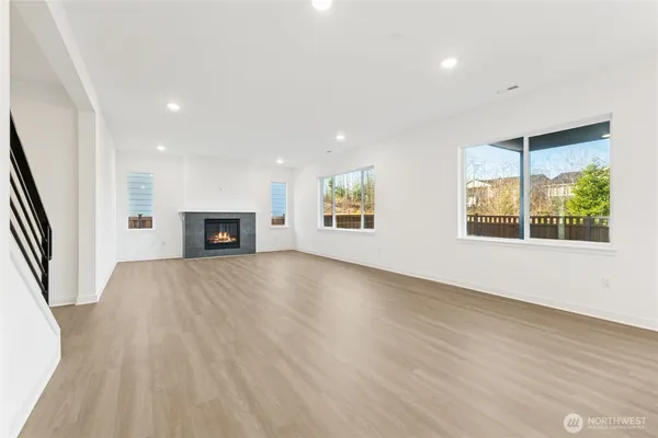 an empty room with windows and fireplace