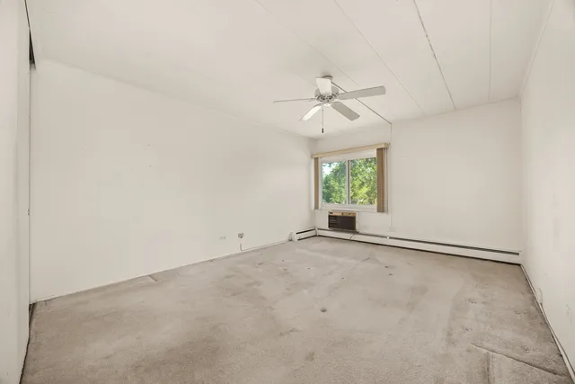 an empty room with windows and chandelier fan