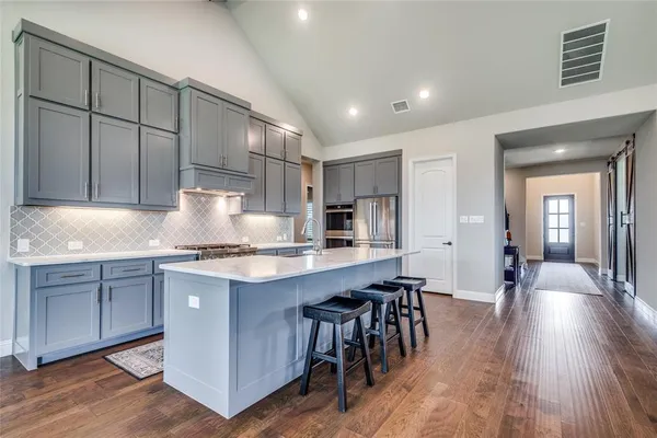 a kitchen with stainless steel appliances granite countertop wooden floors and view living room