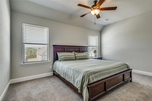 a bed sitting in a bedroom next to a window and a chandelier