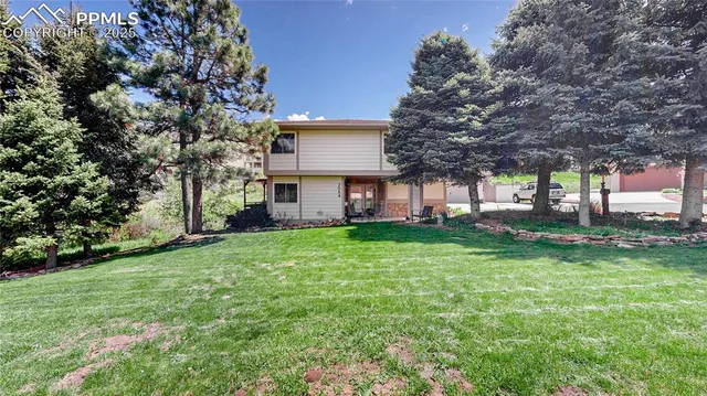 a view of a house with backyard and a tree