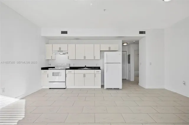 a kitchen with a refrigerator and white cabinets