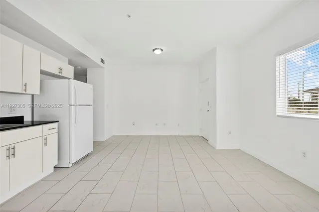 a view of a kitchen with white cabinets and refrigerator