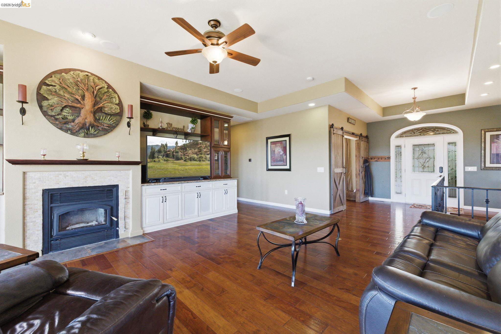 12808 Mammoth Mine Road Jamestown, CA 95327 - Photo 11 of 60 Living area featuring a barn door, dark wood finished floors, ceiling fan, recessed lighting, and a tiled fireplace