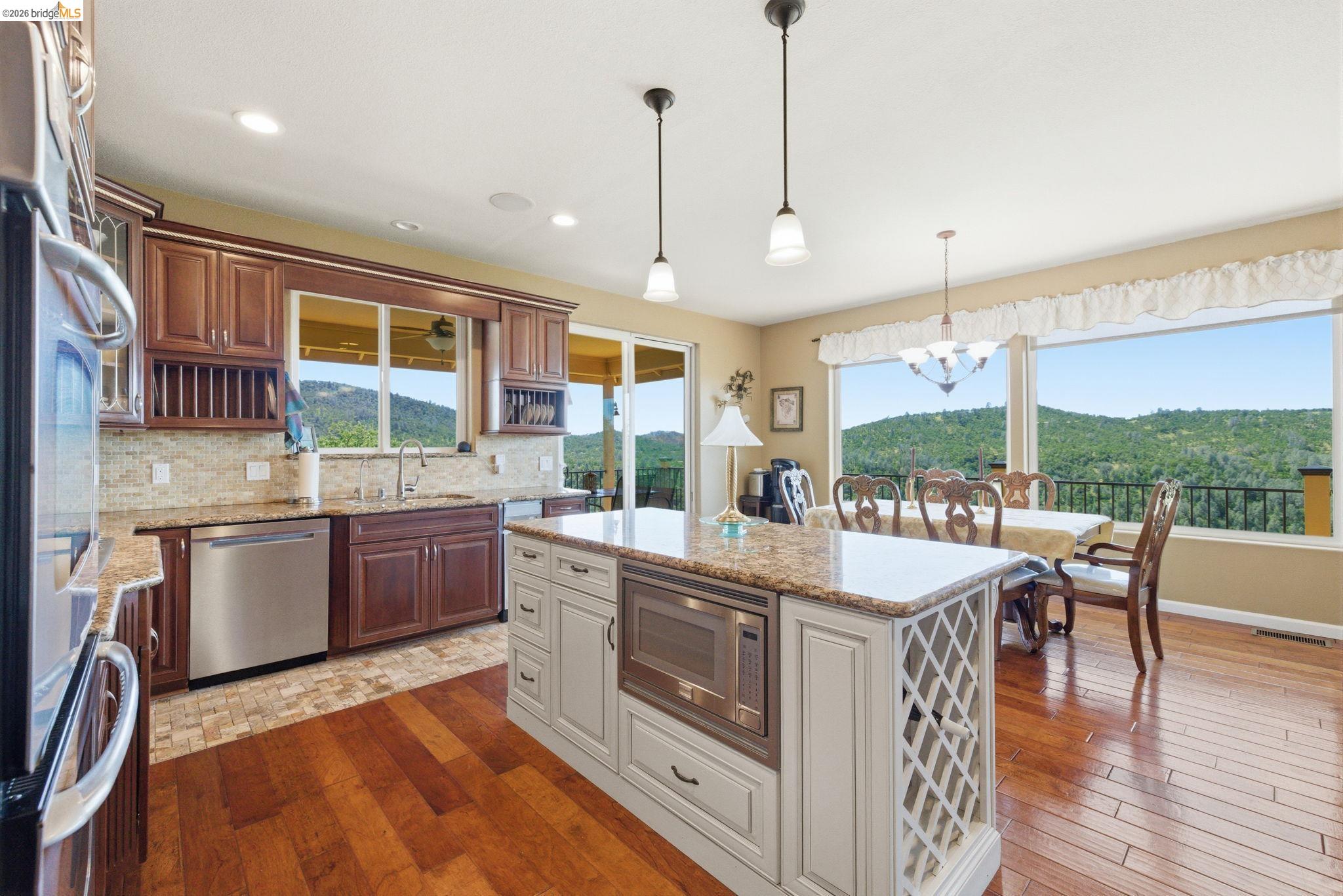 12808 Mammoth Mine Road Jamestown, CA 95327 - Photo 17 of 60 Two tone kitchen featuring stainless steel appliances, light stone counters, dark wood finished floors, a center island, and a chandelier