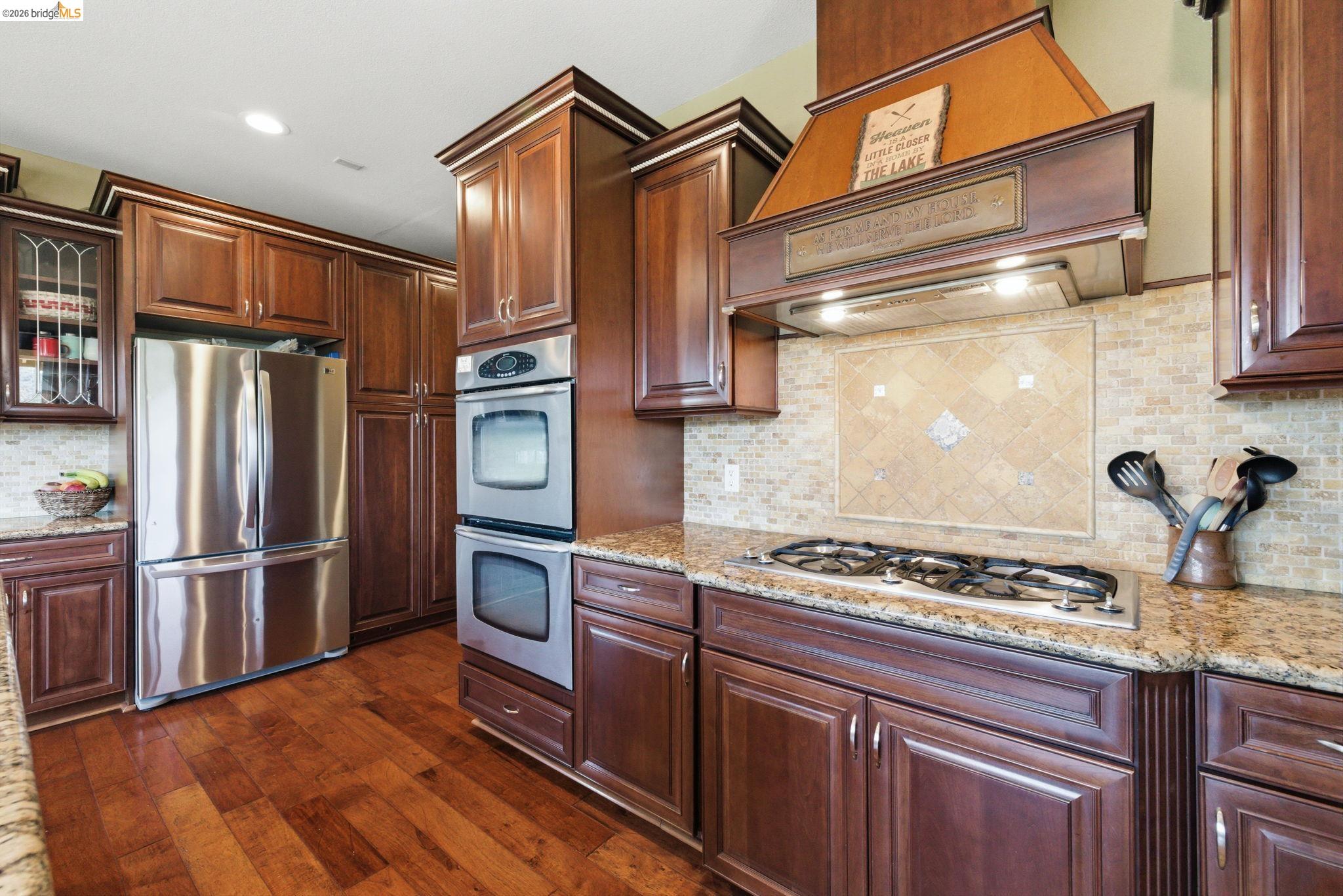 12808 Mammoth Mine Road Jamestown, CA 95327 - Photo 19 of 60 Kitchen with stainless steel appliances, dark wood-type flooring, light stone counters, glass insert cabinets, and recessed lighting