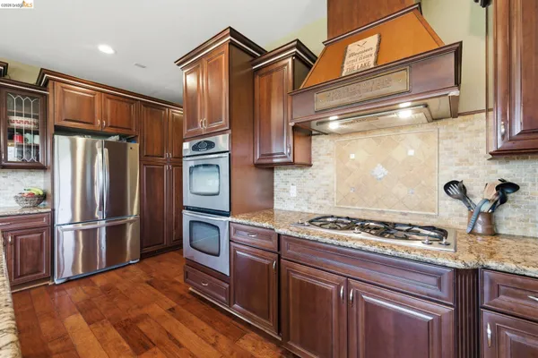 a kitchen with stainless steel appliances granite countertop a refrigerator and a stove top oven