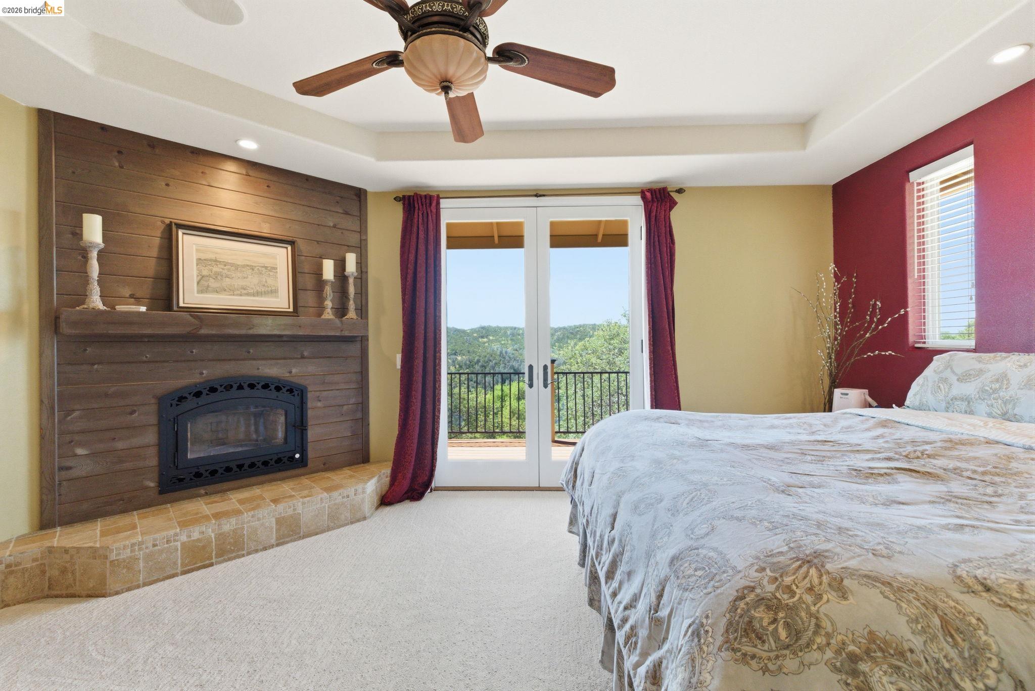 12808 Mammoth Mine Road Jamestown, CA 95327 - Photo 21 of 60 Bedroom with access to exterior, ceiling fan, light colored carpet, a tray ceiling, and a fireplace