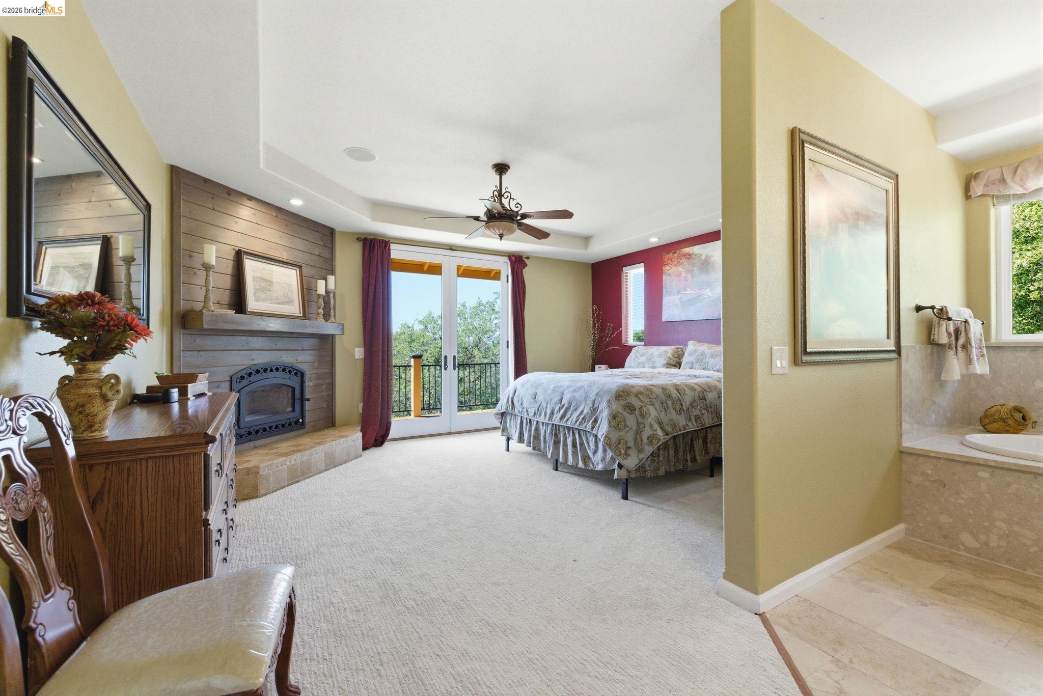 12808 Mammoth Mine Road Jamestown, CA 95327 - Photo 22 of 60 Bedroom featuring access to exterior, a fireplace with raised hearth, light colored carpet, ceiling fan, and french doors