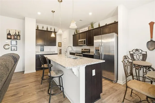 a kitchen with stainless steel appliances a refrigerator a stove a dining table and chairs with wooden floor