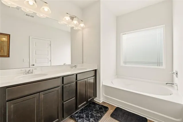 a bathroom with a tub a sink and a mirror