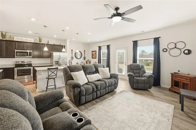 a living room with furniture kitchen view and a chandelier