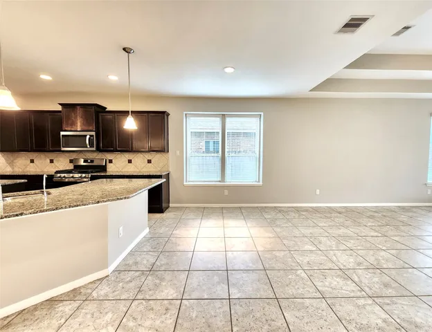 a large kitchen with kitchen island granite countertop a large counter top a sink a stove a dining table and chairs