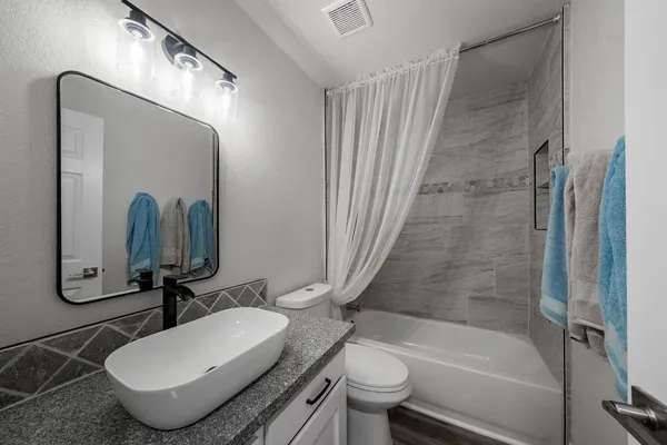 a bathroom with a granite countertop sink mirror toilet and bathtub
