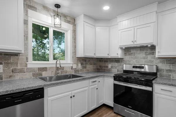 a large kitchen with kitchen island a stove a sink dishwasher and a refrigerator with wooden floor