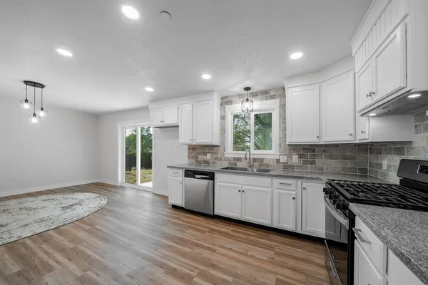 a kitchen with stainless steel appliances a stove top oven a sink cabinets and a wooden floor