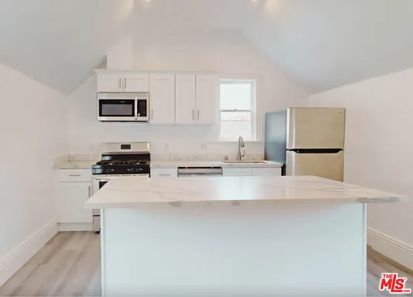 a large white kitchen with kitchen island a sink a stove and a refrigerator