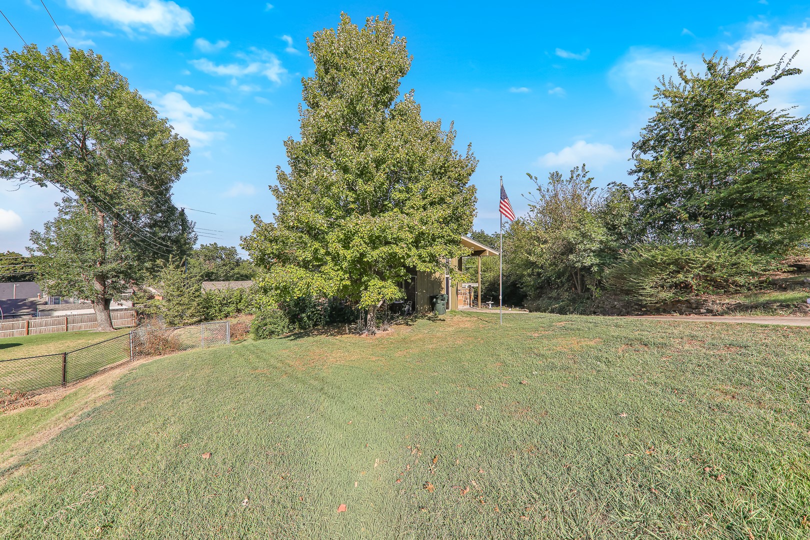 750 Risser Avenue Muskogee, OK 74403 - Photo 23 of 24 Expansive grassy yard with mature trees and a chain-link fence.