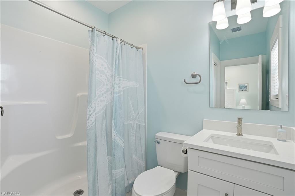 1 Fairview Boulevard Fort Myers Beach, FL 33931 - Photo 17 of 48 Full bathroom featuring a white vanity with an integrated sink, a sleek mirror, and a shower-tub combination with a white surround - Virtually Edited Image