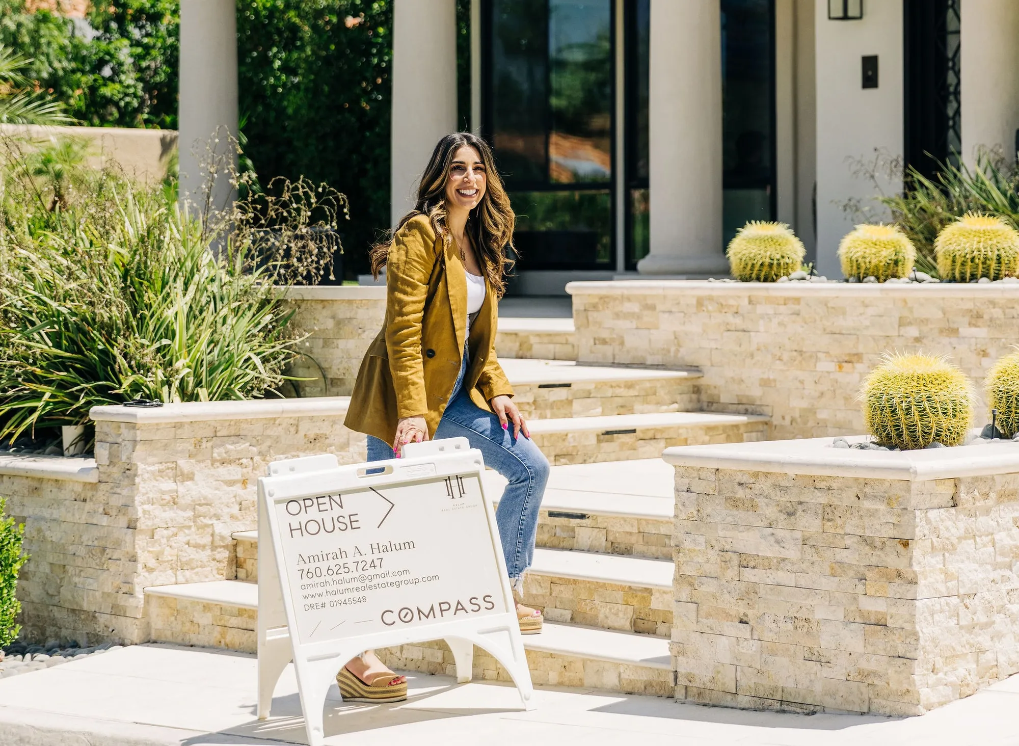 agent holding an open house sign on the front steps of a desert home