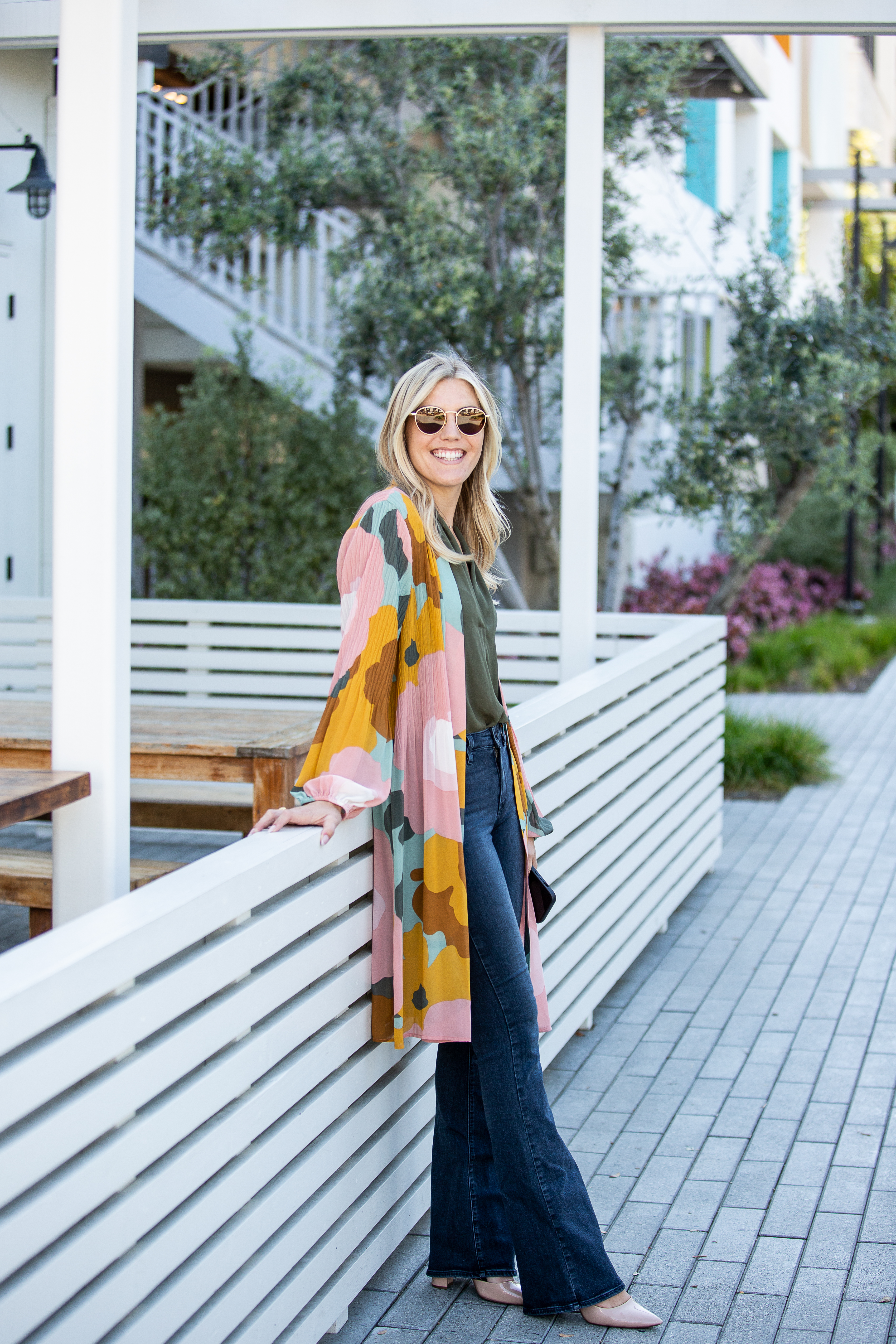 A woman standing on a sidewalk with a balcony.