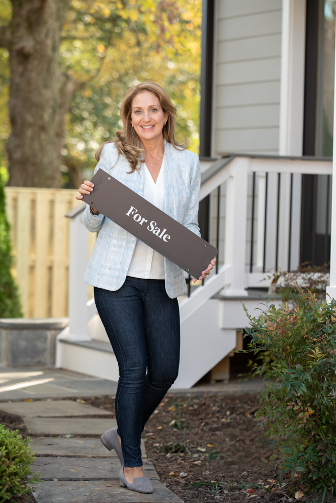 A woman holding a skateboard in front of a house