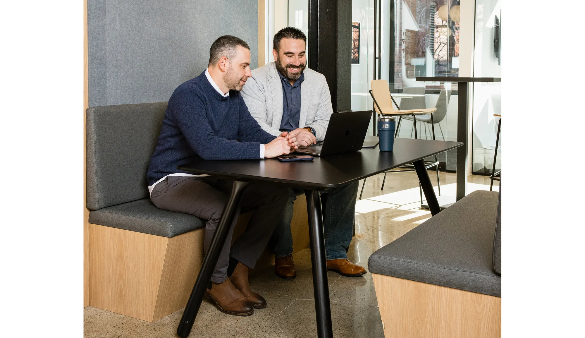 Two men sitting at a table with a laptop