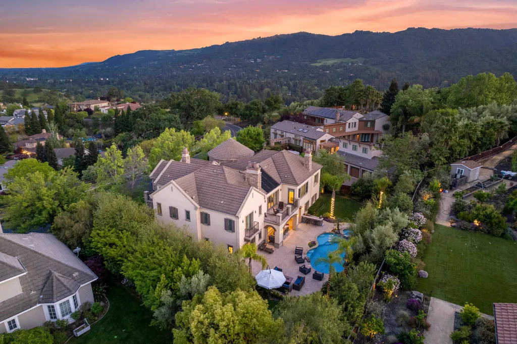 A two story white house with a backyard with chairs at sunset