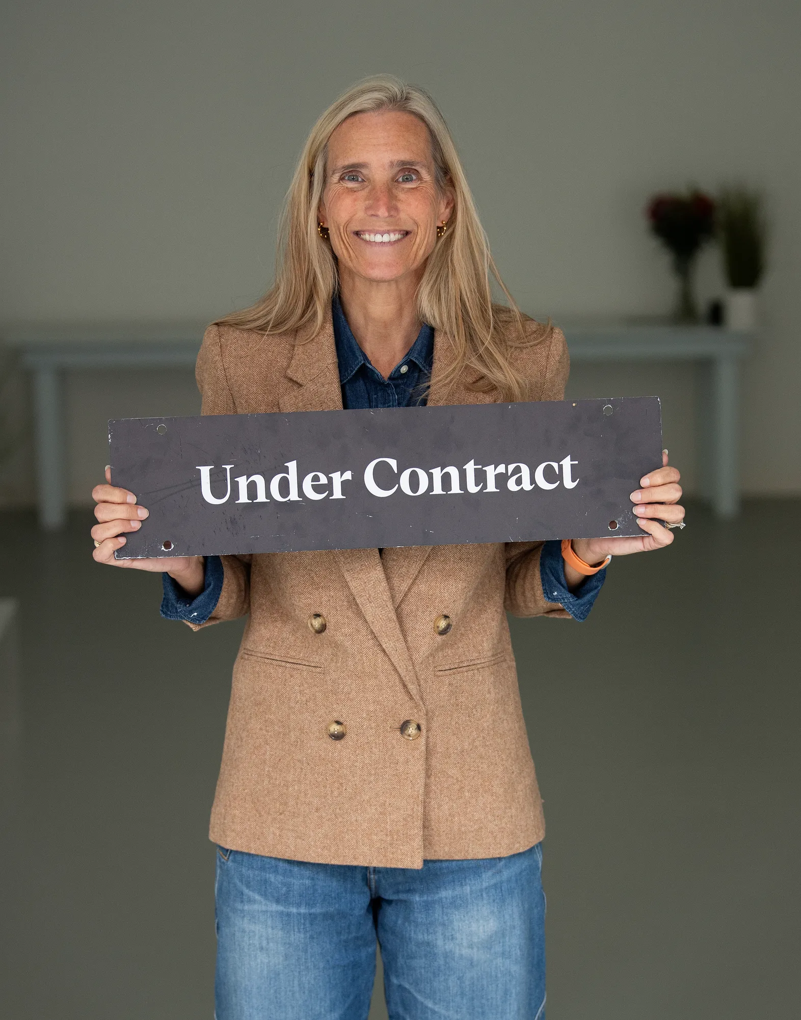 Megan Koppe, Compass real estate agent in Annapolis, MD, holding an Under Contract sign