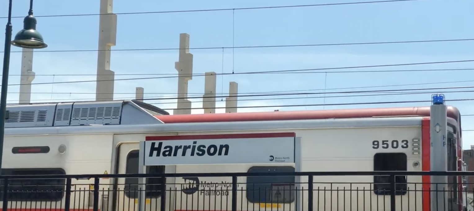 A train on a track near a fence.