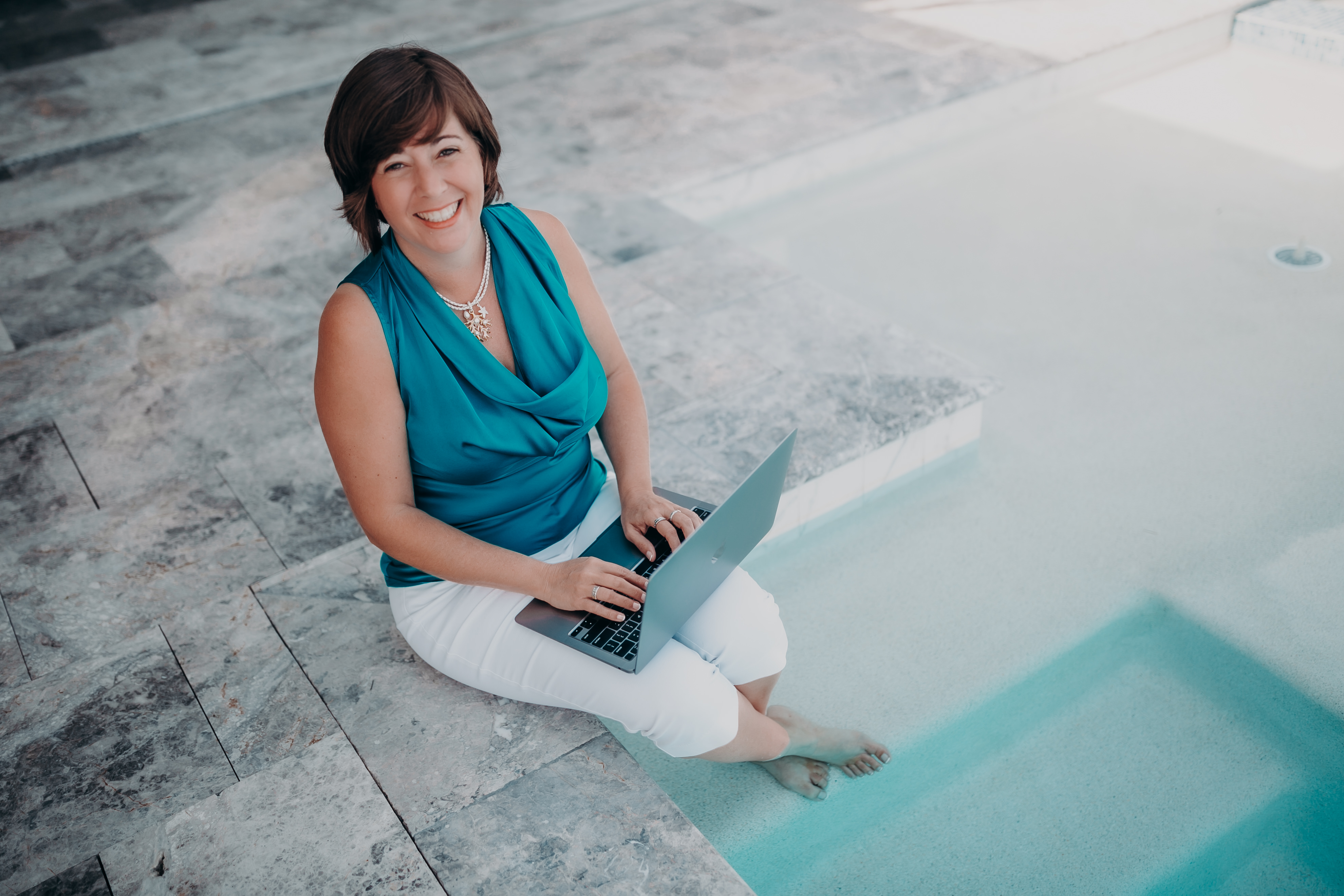 A woman sitting on a concrete bench with a laptop